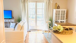 Un salon moderne avec un canapé, un téléviseur, un meuble et un panier en osier posé sur un comptoir.