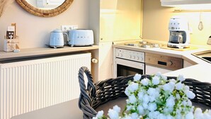 Une cuisine avec des meubles blancs, une cuisinière, un grille-pain et un four à micro-ondes.