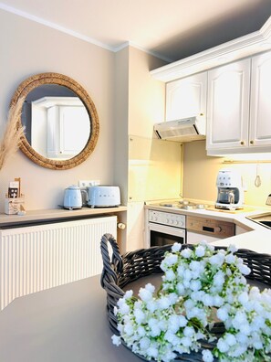 A kitchen with white cabinets, a stove, a toaster, and a microwave. - Apartment 'Idyllische Strandwohnung Zingst' with Private Terrace, Private Garden and Wi-Fi (Zingst)