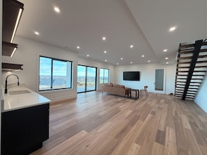Ein modernes Wohnzimmer mit einem großen Fenster, einem Flachbildfernseher und einer Treppe.