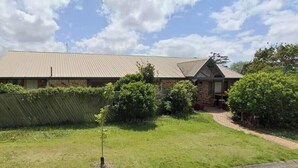 A two-story building with a flat roof, surrounded by a well-maintained lawn and a wooden fence. - Bonhaven Deluxe King Room with private Bathroom (Runcorn)