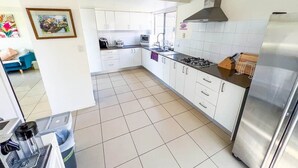 A modern kitchen with white cabinets, a stainless steel range, and a tiled floor. - Unique Japanese Ensuite Room futon tatami 3 people (Runcorn)