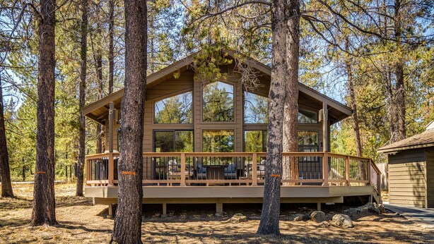 A cabin with a deck, surrounded by trees. - Cozy Sunriver Gateway: SHARC, Beautiful Windows, Deck, Games, Bikes (Sunriver)