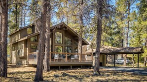 A cabin with a deck, surrounded by trees. - Cozy Sunriver Gateway: SHARC, Beautiful Windows, Deck, Games, Bikes (Sunriver)
