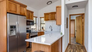 A kitchen with wooden cabinets, stainless steel appliances, a central island, and a trash can. - Cozy Sunriver Gateway: SHARC, Beautiful Windows, Deck, Games, Bikes (Sunriver)