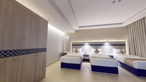 A hotel room with a large wardrobe, two beds with matching headboards, and a modern light fixture. - Al Mustarah Hotel (Madinah)