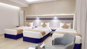 A hotel room with two beds, a desk, a chair, and a mirror. - Al Mustarah Hotel (Madinah)