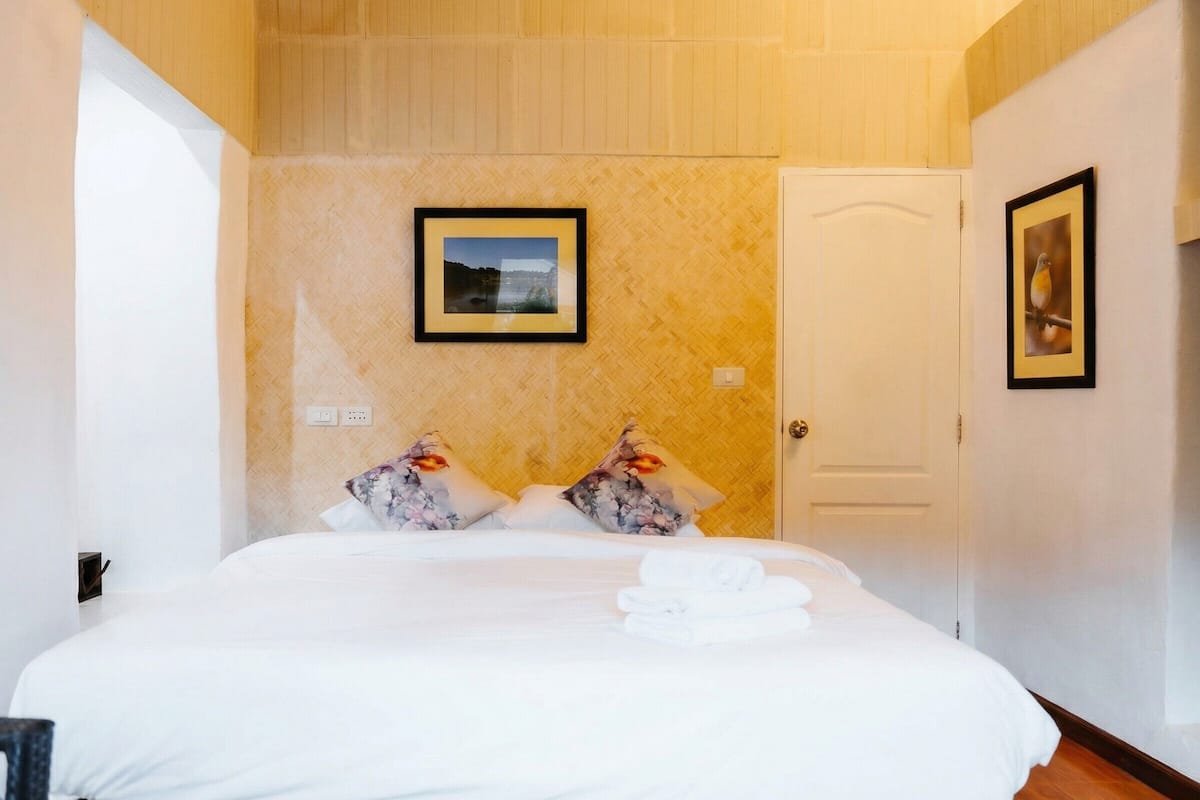 A hotel room with a bed, a door, and two framed pictures on the wall.