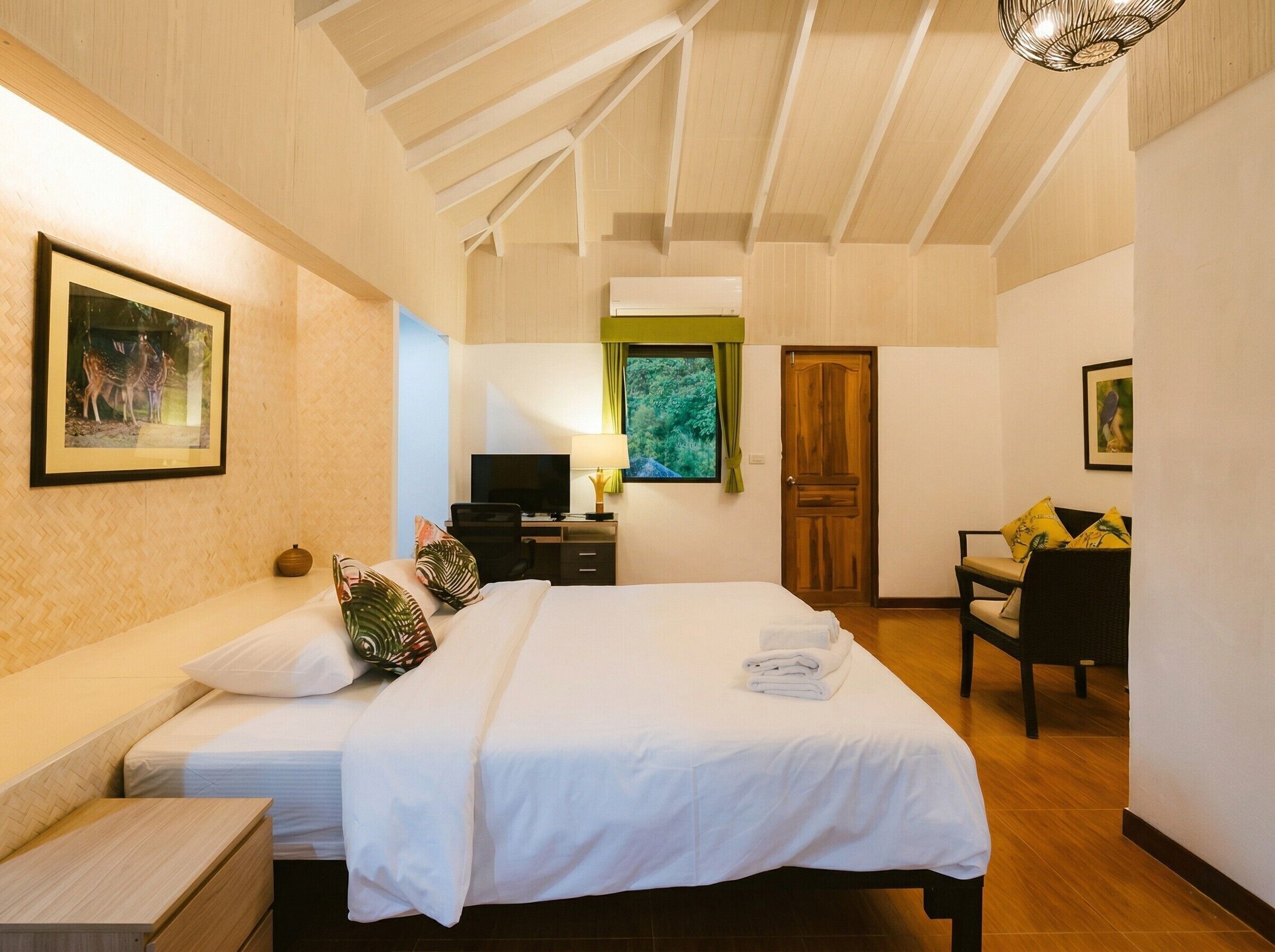 A hotel room with a bed, a desk with a computer, a TV, and a chair.