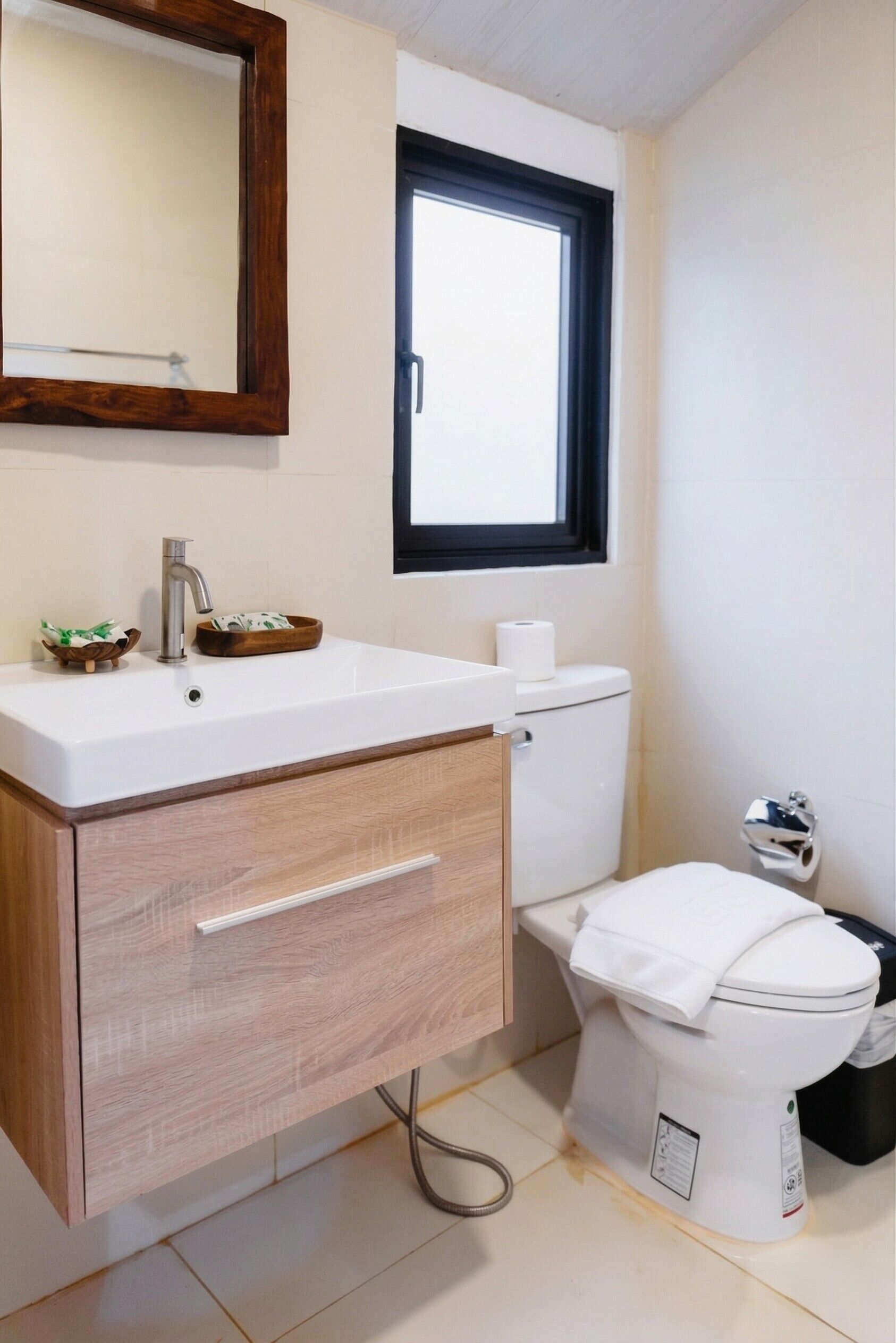 Un baño con lavamanos blanco, mueble de madera y un inodoro.