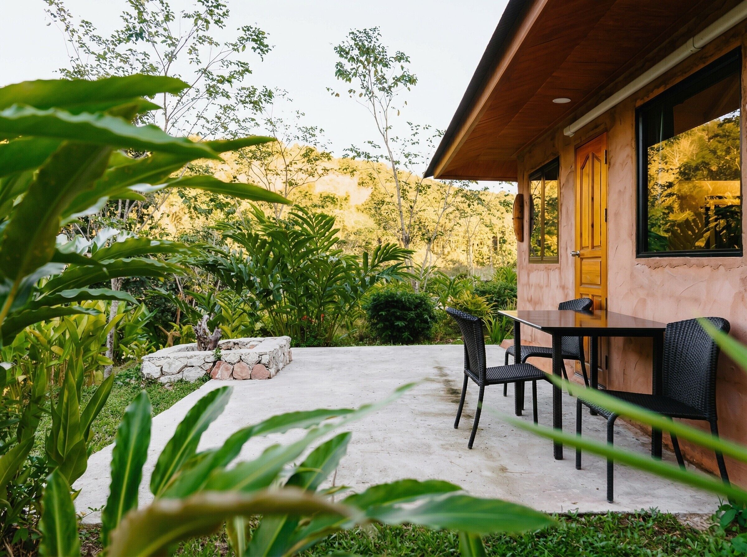 A wooden building with a stone patio, outdoor seating, and lush greenery.