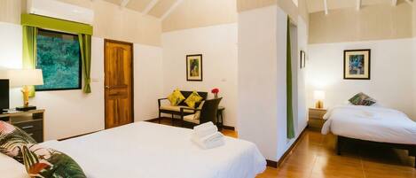 Habitación de hotel con dos camas, techo de madera, cortina verde, un cuadro y una ventana con vistas.