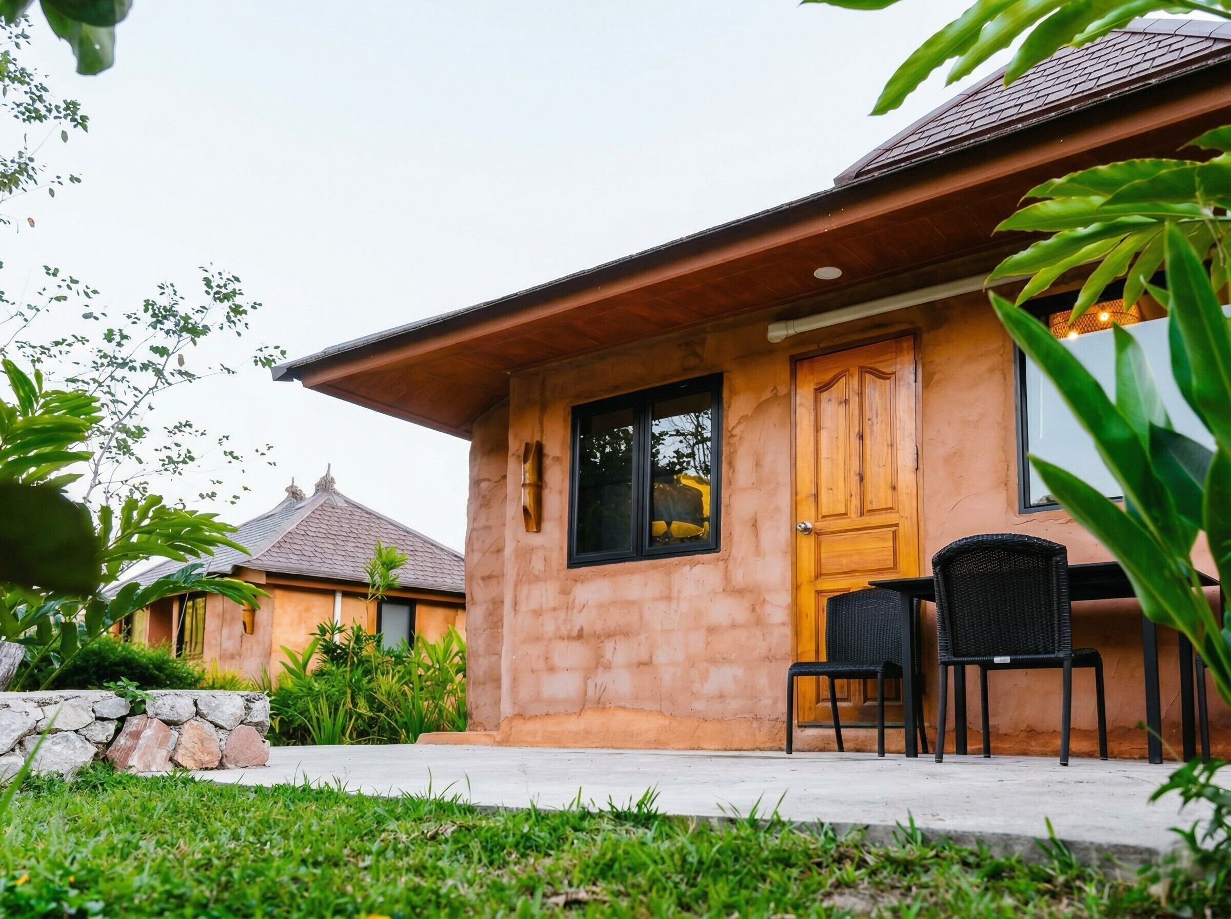 Un bâtiment avec une façade en pierre, une porte en bois et une fenêtre. On peut voir une chaise et une table à l’extérieur.