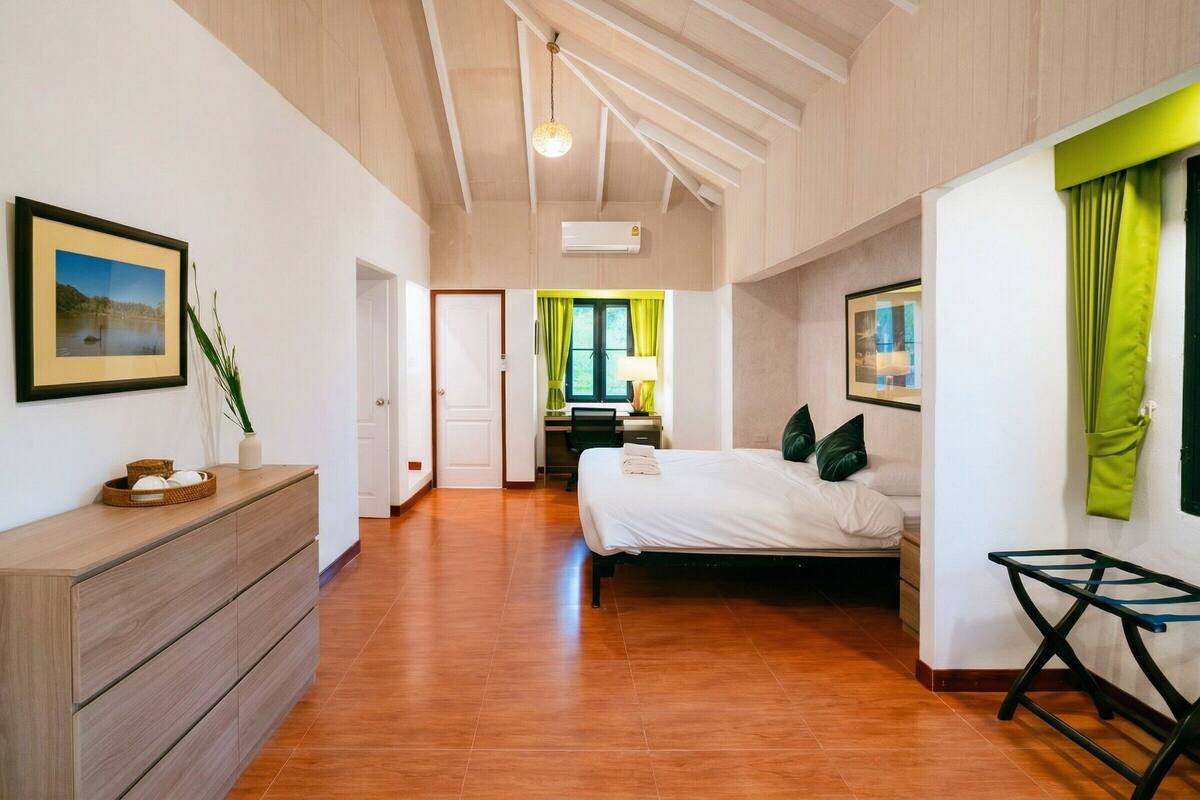 A spacious room with a bed, a desk, and a dresser.