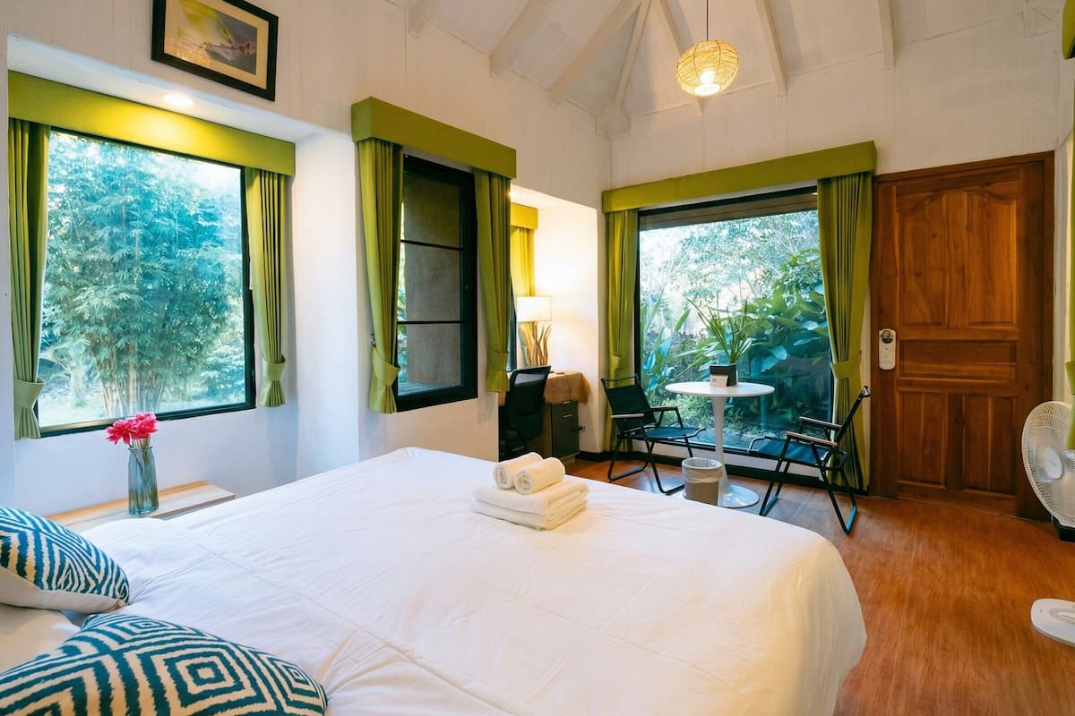 A hotel room with a bed, a desk, a chair, a table, and a door.