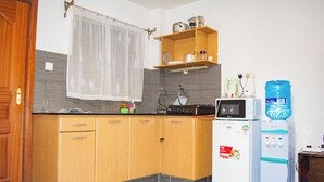 Eine Küche mit Holzausstattung, einer Mikrowelle, einem Wasserspender und einem kleinen Kühlschrank.