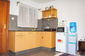 A kitchen with wooden cabinets, a microwave, a water dispenser, and a small refrigerator. - Beautiful studio in Nairobi perfect for your city getaway.
5 minutes from CBD (Nairobi)