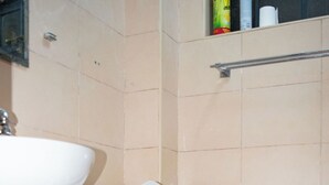 Ein Badezimmer mit Toilette, Waschbecken und Ablage für Pflegeprodukte.