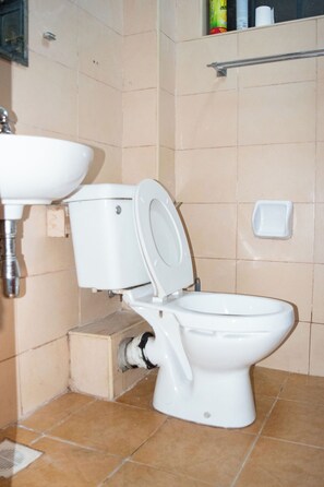 A bathroom with a toilet, sink, and a shelf with toiletries. - Beautiful studio in Nairobi perfect for your city getaway.
5 minutes from CBD (Nairobi)