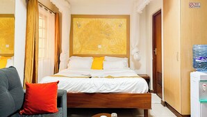Ein Hotelzimmer mit Bett, einer Sitzecke, einem Kleiderschrank und einem Wasserspender.