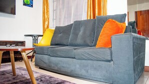 Ein Wohnzimmer mit einer Couch, einem kleinen Tisch und einem Fernseher an der Wand.