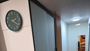 Ein Korridor mit einer Uhr, einer Schiebetür, einem Feuerlöscher und einem Fliesenboden.
