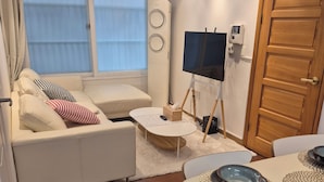 Ein modernes Wohnzimmer mit Sofa, Fernseher und Essbereich mit Tellern.