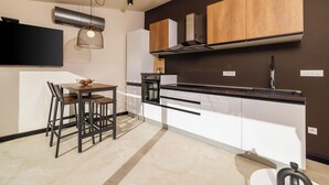 Et moderne køkken med spiseplads, med en sort bordplade, træskabe og en hængende lampe.