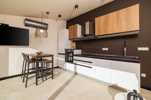Eine moderne Küche mit Essbereich, die eine schwarze Arbeitsplatte, Holzschränke und eine Pendelleuchte zeigt.