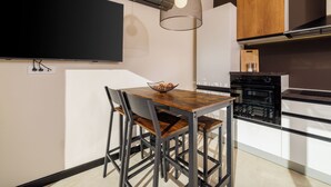 Et moderne køkken med spisebord, stole, fjernsyn og en hængende lampe.