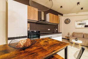 Eine moderne Küche mit Holztisch, Einbauofen und Essbereich mit Sofa und kleinen Beistelltisch.