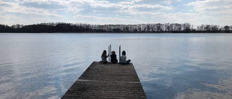 A wooden pier extending into calm water with a clear sky above.
