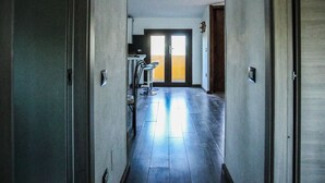 A hallway with a door at the end, a chair, and a light fixture on the wall. - Blue Nest Ottava - A few minutes from Sassari (Ottava)