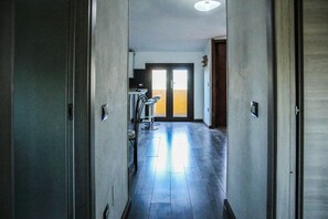 Un passadís amb una porta al final, una cadira i una làmpada de paret.