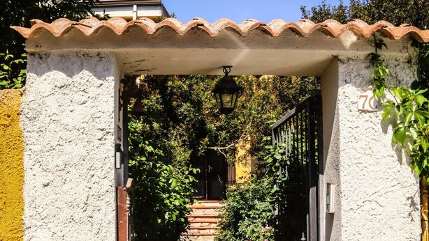 A narrow stone pathway leading to a gated entrance, surrounded by greenery and a white wall. - Blue Nest Ottava - A few minutes from Sassari (Ottava)
