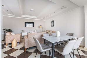 Ein modernes Wohnzimmer mit einer Couch, einem Esstisch und einem an der Wand befestigten Fernseher.