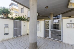 A courtyard with tiled flooring, metal gates, and a building with a number sign. - A cozy studio apartment that comfortably accommodates two people, equipped with every comfort for a pleasant stay, including a furnished balcony for relaxing. The apartment is located in a quiet area, well-equipped with essential amenities, just a 10-min (Lecce)