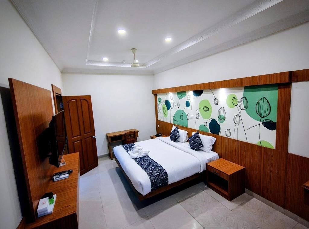 A bedroom with a bed, wooden wardrobe, bedside tables, and a wall with a leaf pattern.