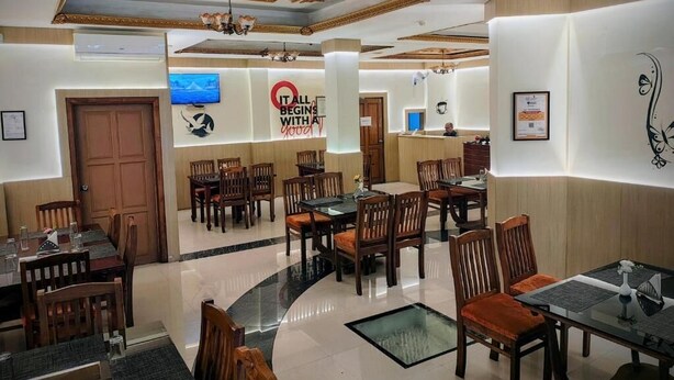 Un comedor de hotel con varias mesas y sillas, un televisor y un cartel que dice 'IT ALL BEGINS WITH YOU'.