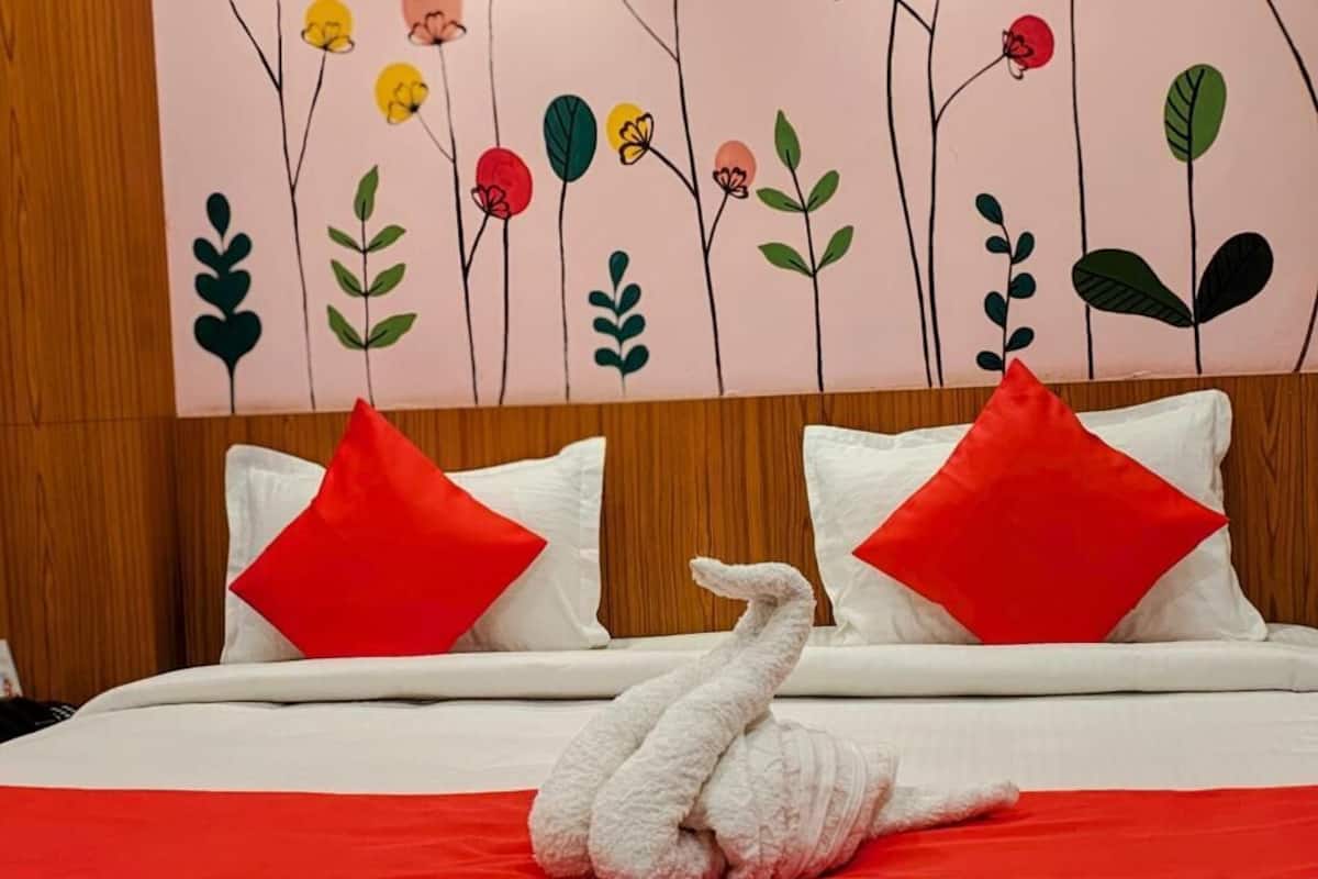 A bed with white bedding, red pillows, and a swan-shaped pillow.