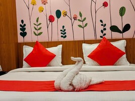A bed with white bedding, red pillows, and a swan-shaped pillow.