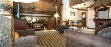 A living room with a fireplace, sofas, a coffee table, and a dining area with chairs.
