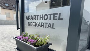 Schild für 'APARTHOTEL NECKARTAL' mit einem Blumenbeet davor.