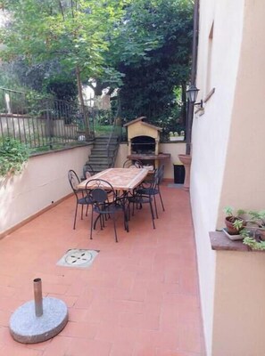 A patio with a table and chairs, a small brick oven, and a potted plant. - The Writing Desk (Scarperia e San Piero)
