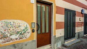 Un edificio con un cartel que indica el número 23, una puerta de madera, una ventana con marco verde y un mural en la pared.