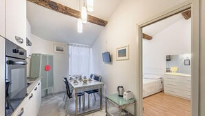 Una cocina compacta con una mesa de comedor, un refrigerador pequeño y un microondas.