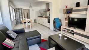 A modern living room with a sofa, coffee table, TV, and kitchen in the background. - Renovated house with equipped kitchen in La Roche-Posay (La Roche-Posay)
