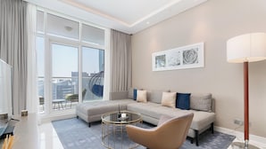 A modern living room with a sectional sofa, a round coffee table, and a floor lamp. - Gala Guests - Maison Prive Collection (Dubai)