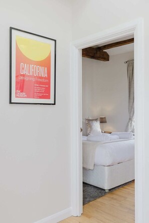 A bedroom with a bed, a nightstand, and a framed picture on the wall. - Stunning 2BR/2BA w/Views & AC (Greater London)