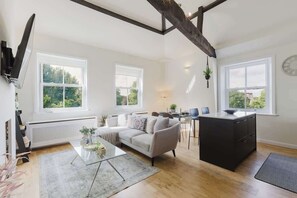 A modern living room with a sofa, coffee table, and a black kitchen island. - Stunning 2BR/2BA w/Views & AC (Greater London)